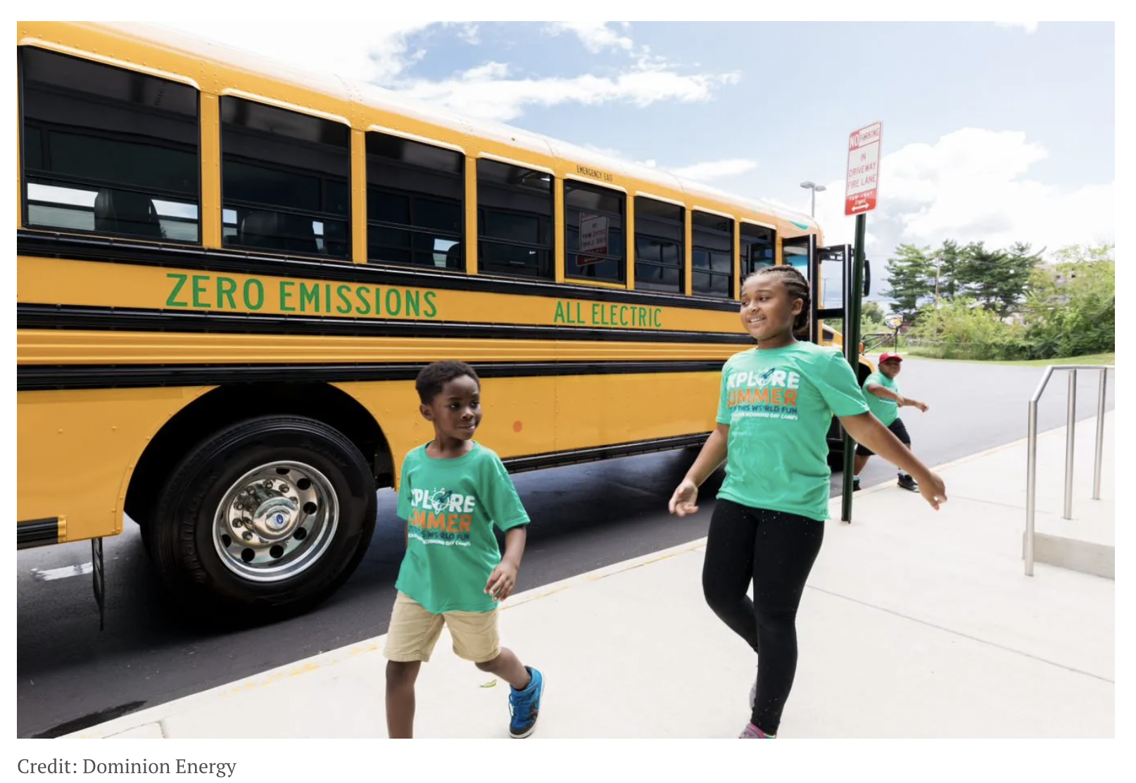Electric school bus behind 2 black school kids