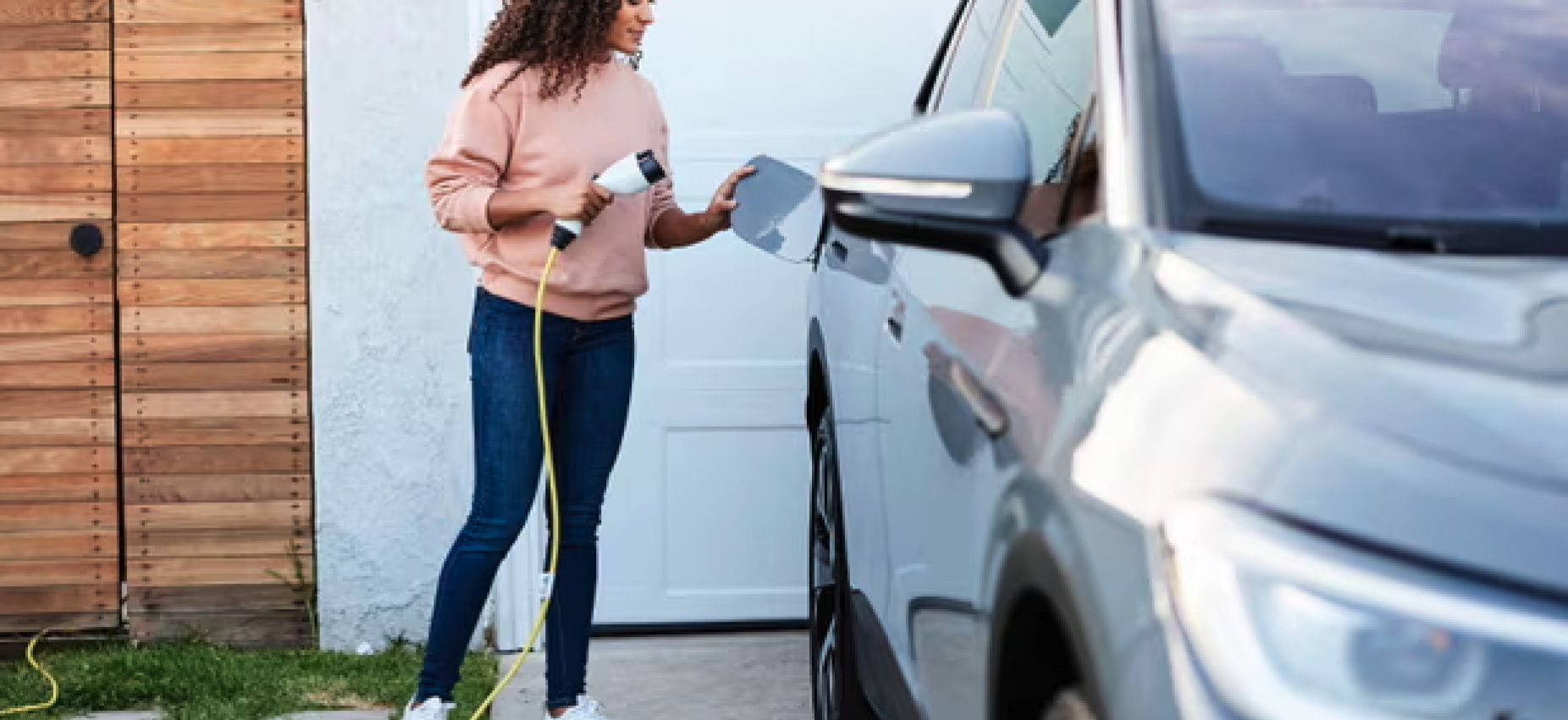 Woman of color charging EV at home