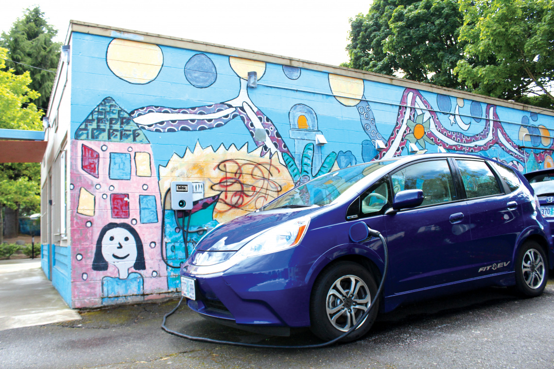 Blue EV charging against a wall with a mural in Hacienda