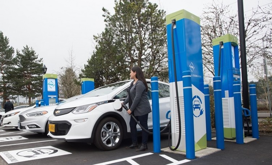 Woman in business attire plugging an EV at a charging station