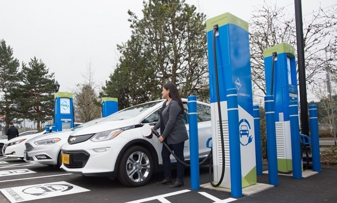 Woman in business attire plugging an EV at a charging station