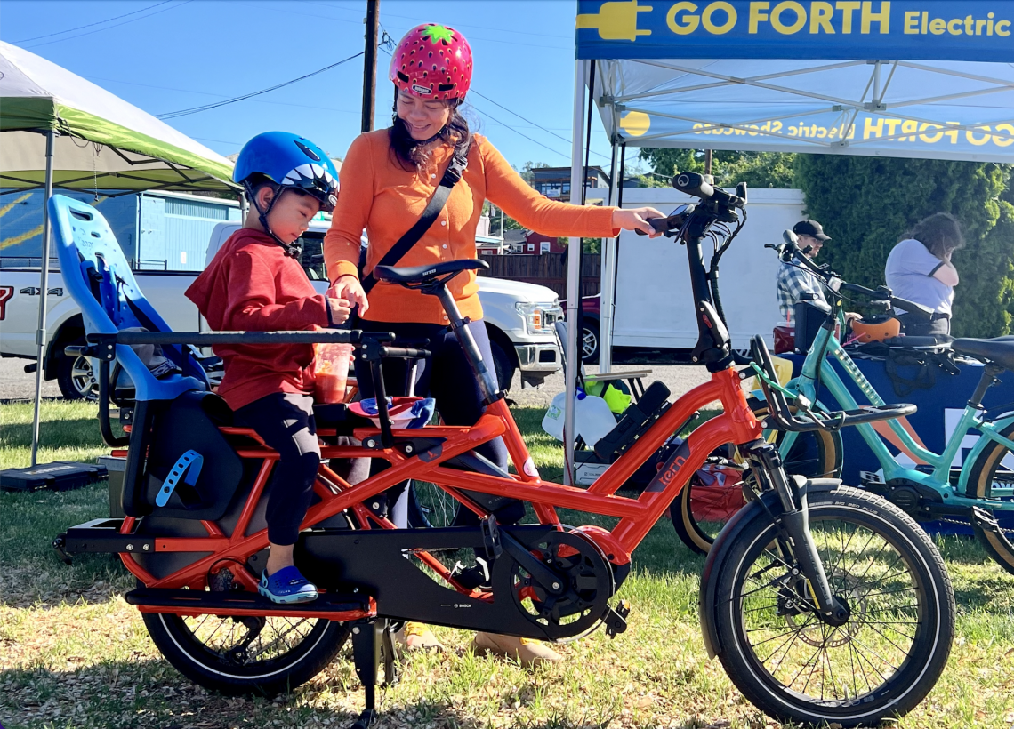 A mother and a child test riding an electric cargo bike.